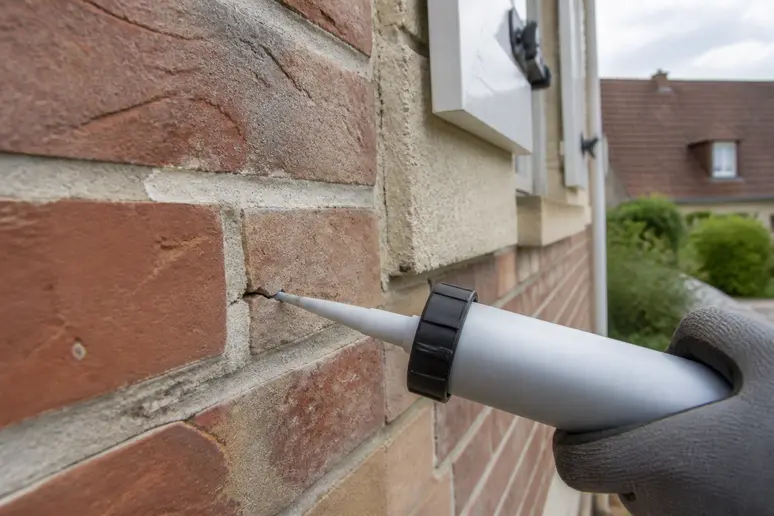 Comment se débarrasser des rats : application mastic pour boucher une fissure extérieure.