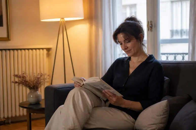 Femme lisant un livre dans un salon à la lumière chaude, ambiance détente 3000k ou 4000k.