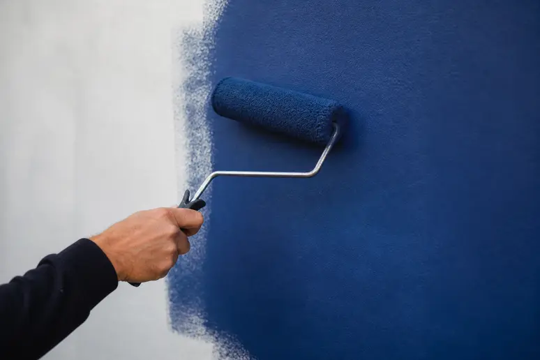 Application minutieuse de la peinture Bleu Majorelle au rouleau sur un mur mat