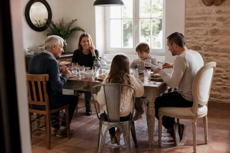 Ensemble de chaises dépareillées autour d'une table en bois chaleureuse dans une salle à manger familiale.