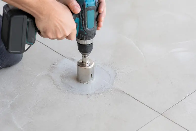 Utilisation d'une scie cloche diamantée sur un carrelage de sol pour les canalisations