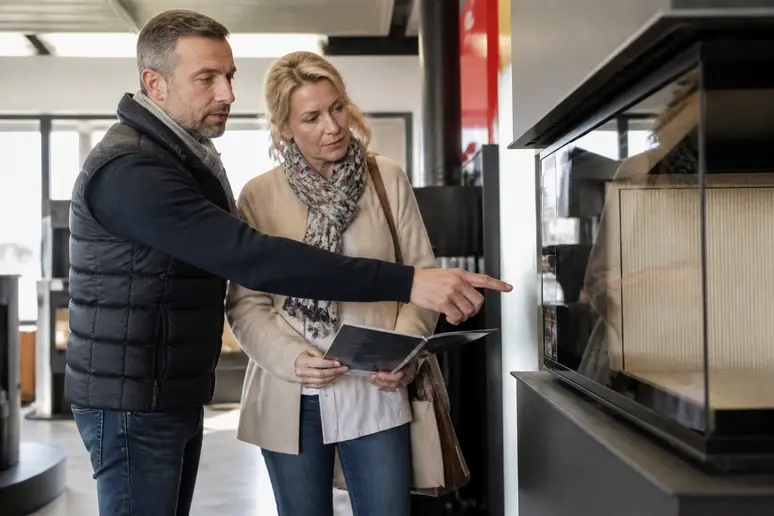Couple examinant un poêle labellisé Flamme Verte, un bon repère pour choisir la bonne marque de poêle à bois à éviter.