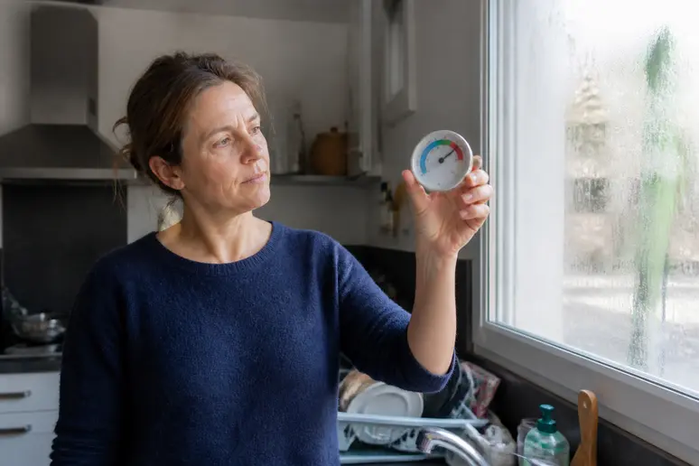 Femme française vérifiant l'humidité dans sa cuisine, signification mille-patte dans la maison