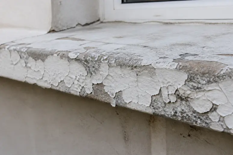 Détail d'une peinture ancienne qui s'écaille sur des appuis de fenetre montrant l'importance d'une bonne préparation.