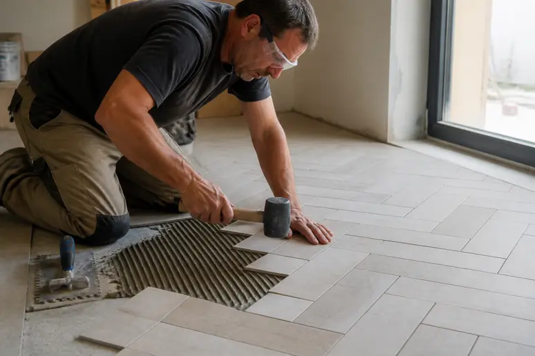 Artisan français appliquant de la colle pour la pose carrelage en chevron avec un peigne.
