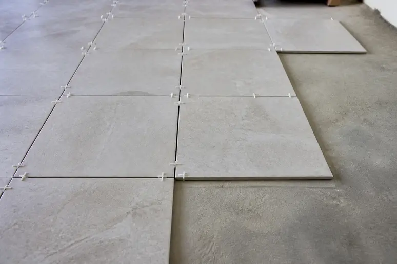 Pose à blanc de carreaux de sol avec des croisillons pour valider le calepinage avant collage.