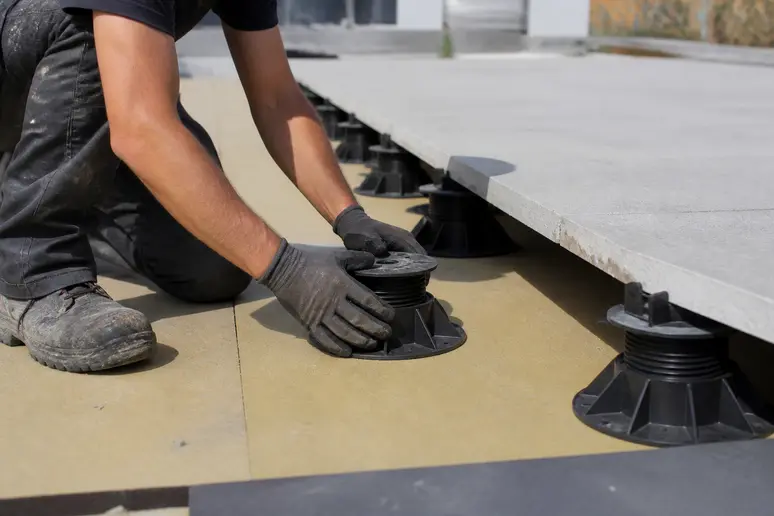 Pose de dalles sur plots réglables au-dessus de l'isolant thermique d'une toiture terrasse.