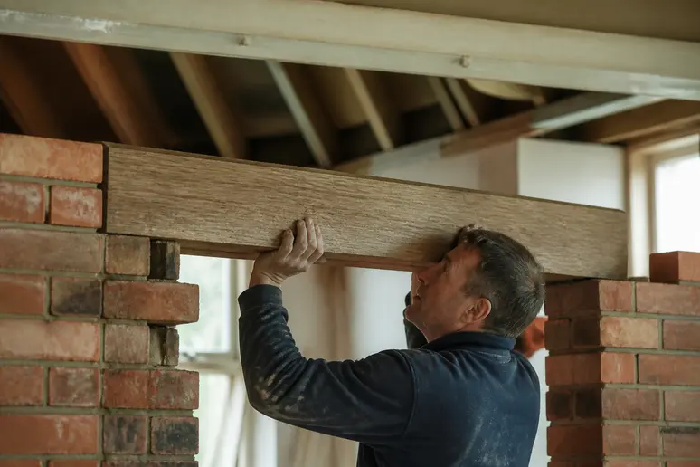 Pose d'un linteau en bois sur un appui en maçonnerie pour une porte