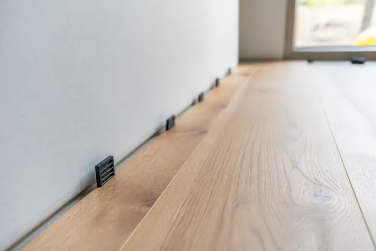 Mise en place des cales d'espacement pour respecter le jeu périphérique de dilatation du parquet.