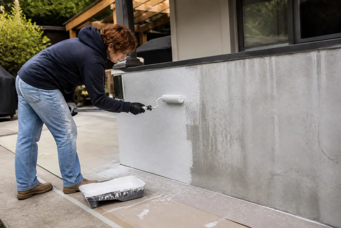 Personne appliquant de la sous-couche au rouleau pour peindre sur du béton extérieur de manière durable