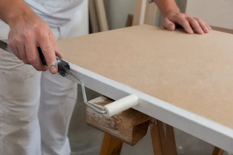 Application d'une sous-couche de peinture sur plinthe MDF brute posée sur tréteaux