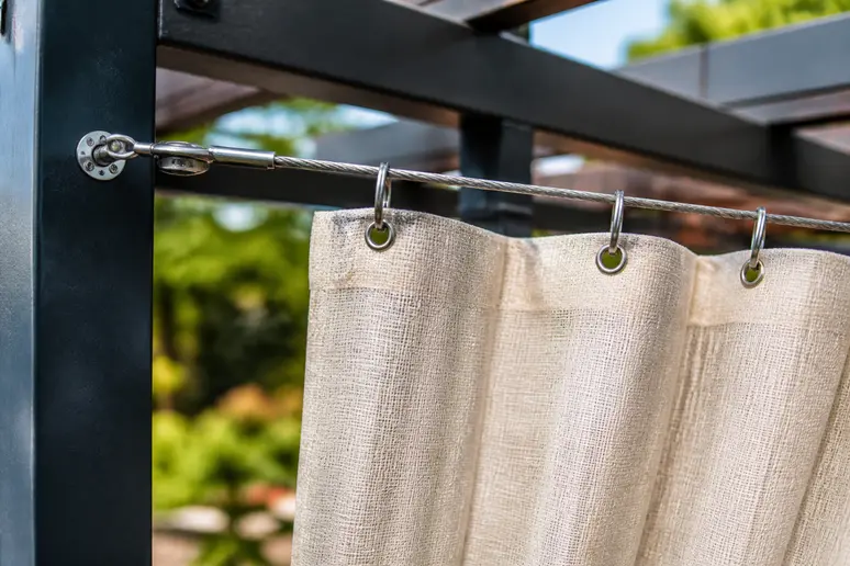 Installation d'un câble en acier tendu pour guider des rideaux de pergola en extérieur
