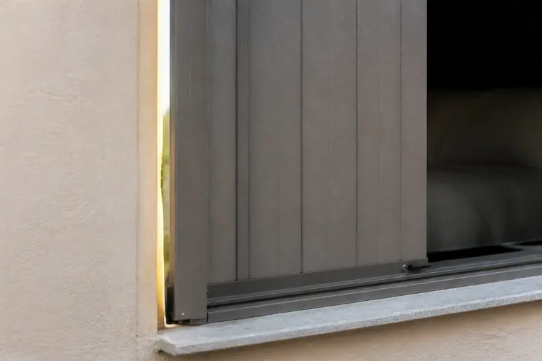 Espace périphérique entre un volet coulissant et le mur de la chambre laissant passer la lumière