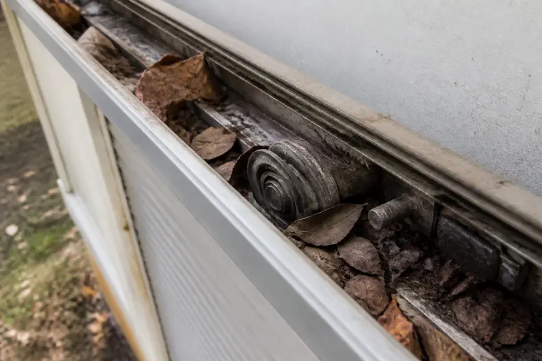 Rail supérieur d'un volet coulissant encrassé par des feuilles et de la poussière extérieure