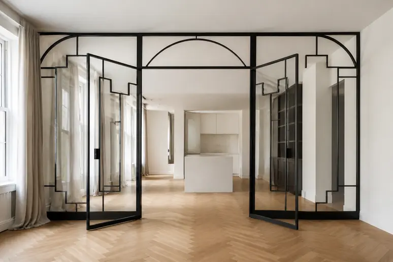 Verrière Art Déco en acier noir avec motifs géométriques et impostes cintrées dans une pièce lumineuse