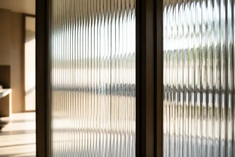 Gros plan sur les rainures verticales d'un verre cannelé de verrière diffusant la lumière naturelle